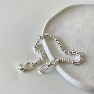 Minimalist 925 silver beaded bracelet featuring a polished heart pendant on a ceramic tray