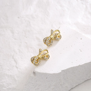 Minimalist 18K gold plated bow earrings with cubic zirconia stones on stone pedestal