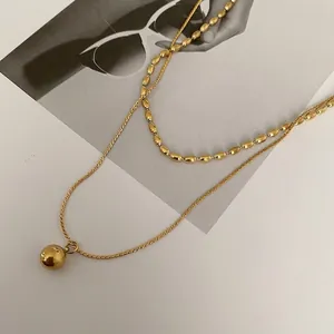 Elegant 18K gold-plated double-layer necklace with beads and spherical pendant on magazine