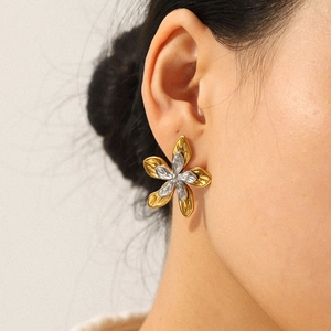 Two-tone gold and silver flower stud earrings worn by a model in a side profile shot
