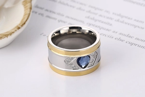 Detail of wide two-tone steel ring with blue heart crystal and white side stones