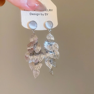 Detailed shot of silver leaf tassel earrings with cat eye stones on a jewelry card
