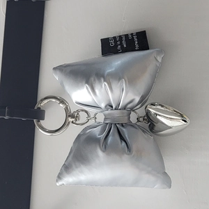 Close-up of silver padded bow keychain with heart pendant and metallic finish