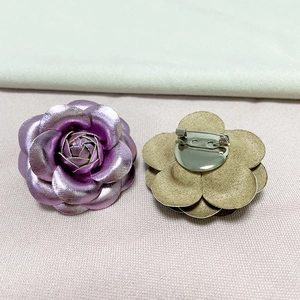Detailed view of purple metallic camellia brooch showing front flower and back pin closure