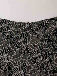 Close-up of intricate white leaf embroidery on high-waist black skirt fabric and stitching