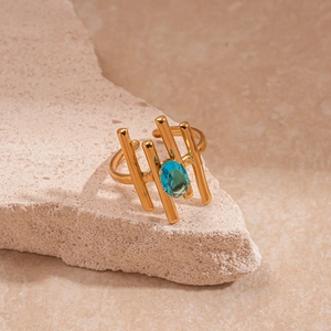 Détail d'une bague dorée texturée avec zircon bleu ovale sur un support en pierre