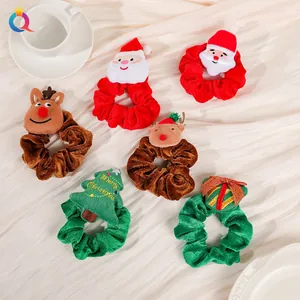 Flat lay of velvet Christmas scrunchies with Santa, reindeer and tree charms in warm tones