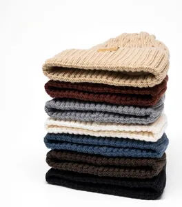 Detail of thick chunky knit beanies in various colors with leather brand patch