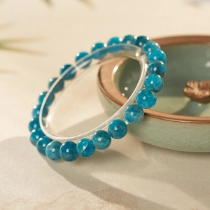 Macro shot of semi-transparent blue apatite crystal beads with natural textures on a porcelain bowl