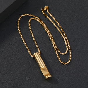 Detailed top view of a gold cylindrical geometric pendant necklace on a black textured surface