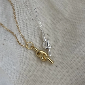 Macro detail of minimalist knotted pendant necklaces in polished gold and silver finish