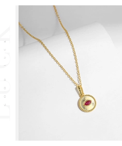 Detailed macro view of a gold vintage round pendant featuring a red marquise-cut gemstone