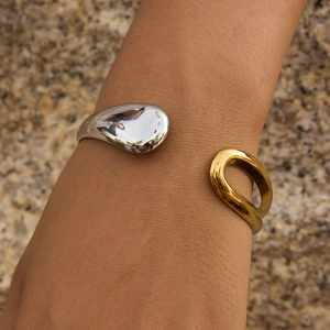 Detail of two-tone 18K stainless steel open bangle with teardrop and U-shape design