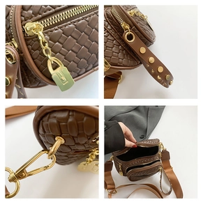 Detailed view of brown woven crossbody bag with gold zippers and studded strap details