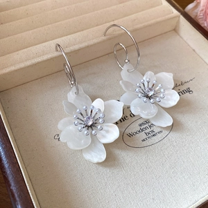 Detailed macro of white floral resin earrings with pearl and rhinestone center accents