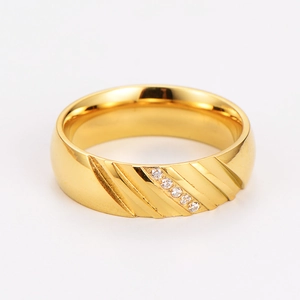 Detail view of a wide gold stainless steel ring featuring diagonal stripes and five small diamonds
