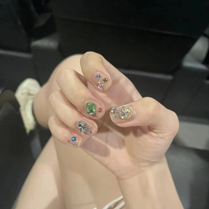 Close-up of handmade press-on nails with multi-color rhinestones and 3D gemstones