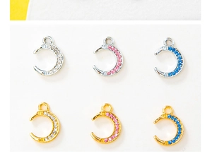Macro detail of six crescent moon charms in silver and gold with multi-color rhinestones