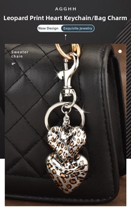 Close-up of leopard print heart charms hanging on a black quilted leather handbag