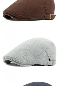 Detail of knitted cotton beret hats in brown, grey, and navy with adjustable metal buckles