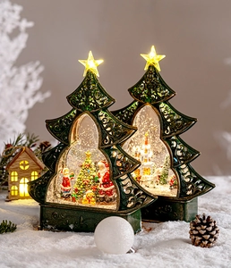 Close-up of glowing Christmas tree snow globes with Santa Claus and festive LED lights