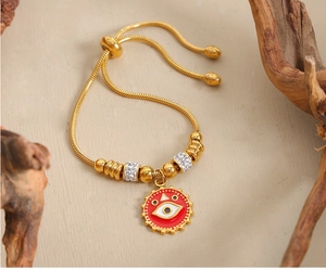 Detail of 18k gold plated snake chain bracelet featuring red enamel evil eye pendant