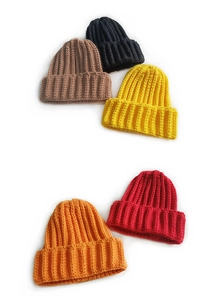 Detail showing various colors of wide ribbed knit beanies in brown, black, and orange