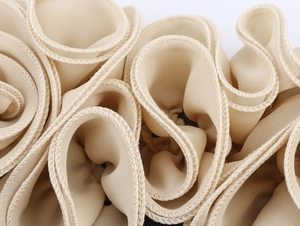 Dettaglio ravvicinato di fiori in rete 3D e volant su un top corto beige chiaro