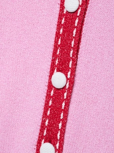 Macro detail of pink knit fabric with red trim and white fabric-covered buttons