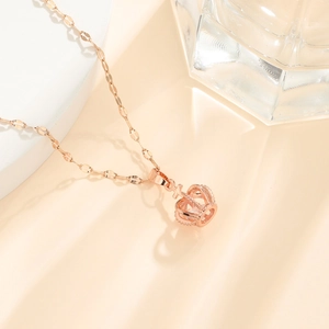 Detail view of a rose gold hollow crown pendant on a sleek flat link chain necklace