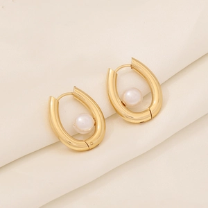 Detail of gold-plated geometric earrings with smooth pearls on white silk texture