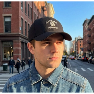Detailed white embroidery on a black cotton baseball cap with urban street background