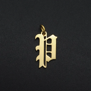 Macro shot of gold stainless steel gothic letter P charm pendant on black background