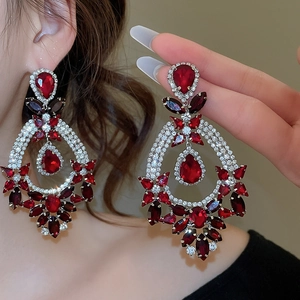 Detail of silver drop earrings with dark red and clear stones worn by a model