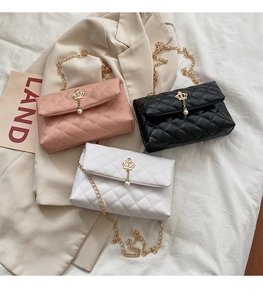 Detailed shot of quilted mini chain bags with crown buckles and pearl drops in three colors