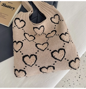 Détail du sac fourre-tout en tricot beige avec motifs de cœurs noirs sur tissu décontracté