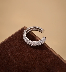 Detailed close-up of a silver C-shaped ear cuff featuring multiple rows of micro-paved gems