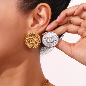 Retro 18K gold and silver petal earrings with embossed eye pattern shown on a model