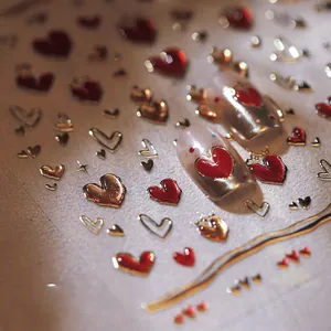 Macro shot of 3D embossed heart nail art stickers with metallic gold edges and red core