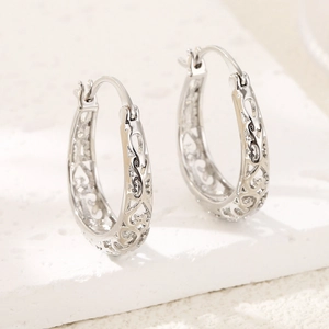 Elegant silver oval hoop earrings with intricate hollow heart pattern for women