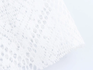 Nahaufnahme der detaillierten Textur des weißen Mesh-Spitzenstoffs auf dem Kleid