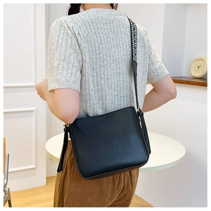 Detail view of black leather bucket bag with stylish ethnic pattern wide shoulder strap