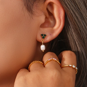 Close-up of elegant 18K gold plated earrings with green emerald and freshwater pearl