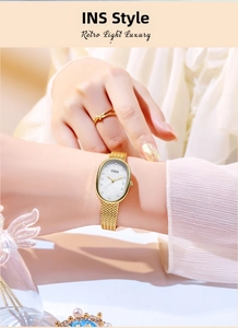 Detail of elegant gold mesh strap and oval watch dial worn on a female wrist