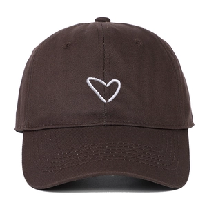 Detailed view of white heart embroidery on a dark brown cotton baseball cap