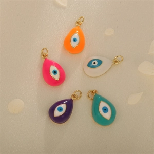 Teardrop evil eye pendants in five colors on beige silk fabric with flower petals