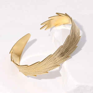Detailed macro view of gold feather texture and polished finish on stainless steel cuff