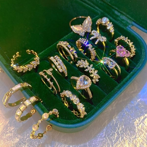 Elegant gold ring set with zircon and pearls displayed in a green velvet jewelry box