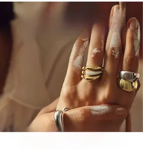 Artistic detail of gold and silver layered rings on fingers with creative paint background