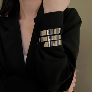 Dettaglio del bracciale a spirale geometrico argentato multistrato indossato su un blazer